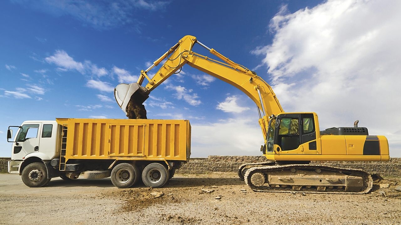 yellow excavator loading mud into a truck