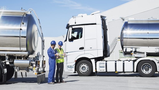 two technicians between two heavy oil trucks