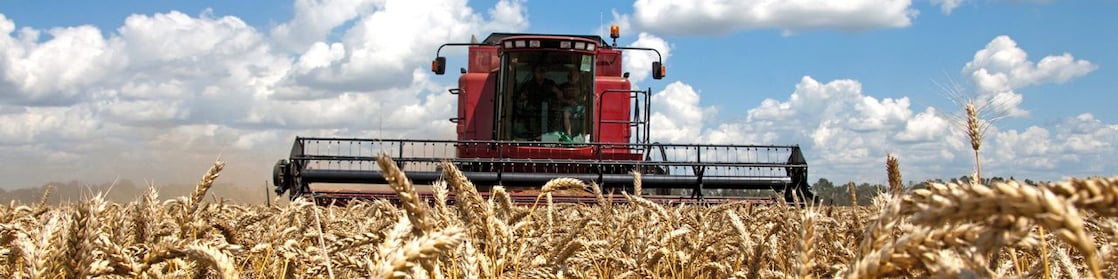 tractor on a field under a blue sky with clouds