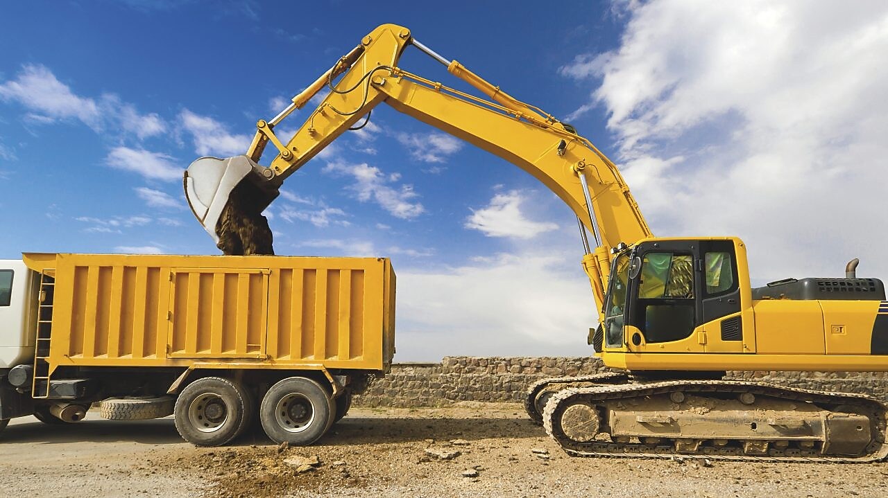 yellow excavator loading mud into a truck