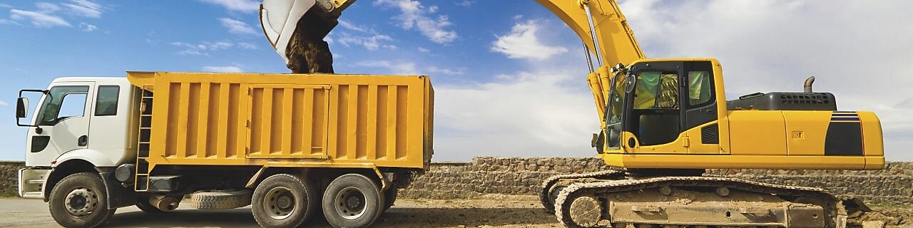 Yellow excavator loading mud into a truck