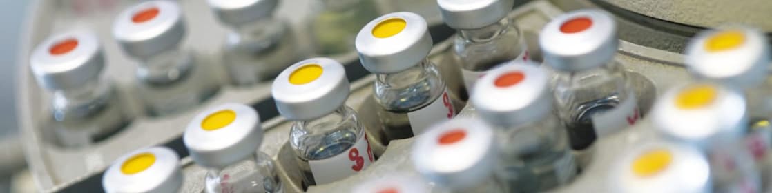 Rows of medicine vials sitting in a holder, some with red dots on the lid, and some with yellow dots on the lid