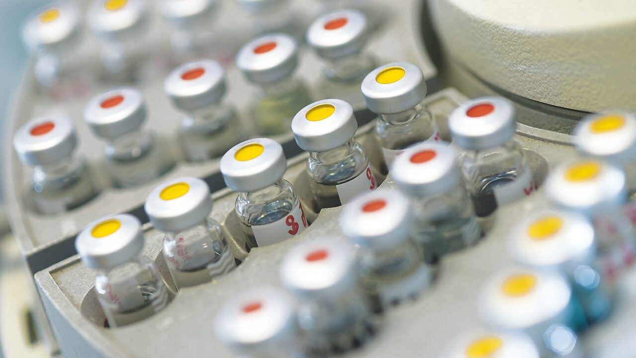 Rows of medicine vials sitting in a holder, some with red dots on the lid, and some with yellow dots on the lid