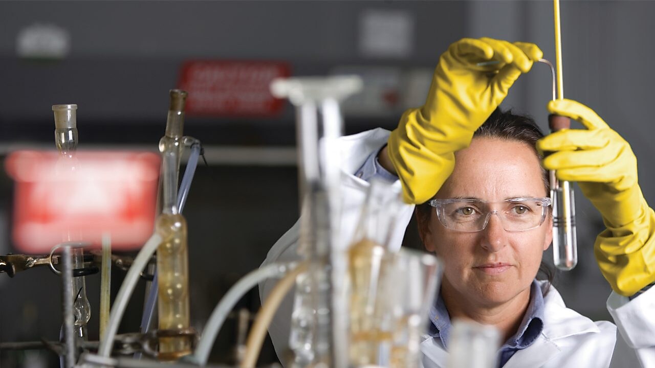 lady in safety goggles conducting a lab experiment