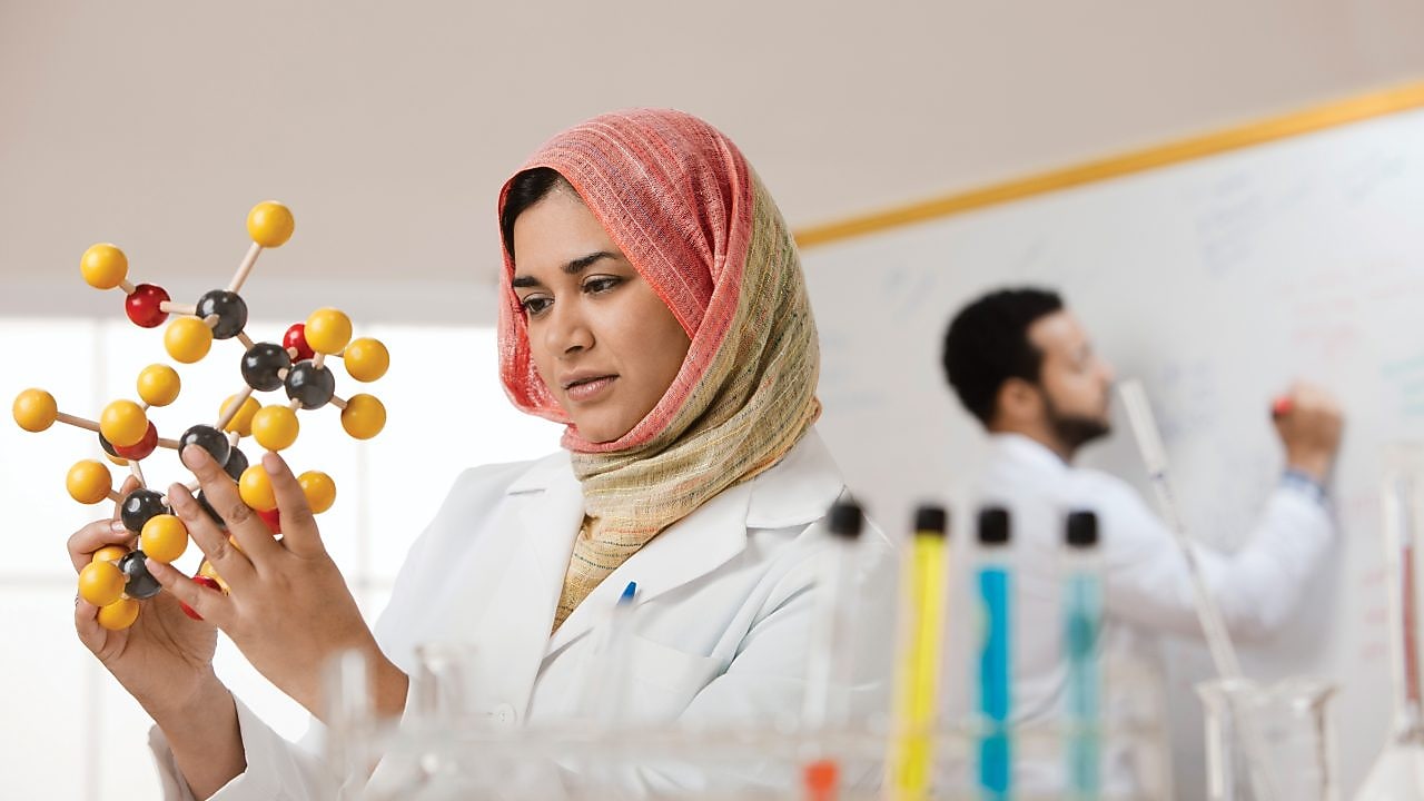 Young female scientist examining a molecular model