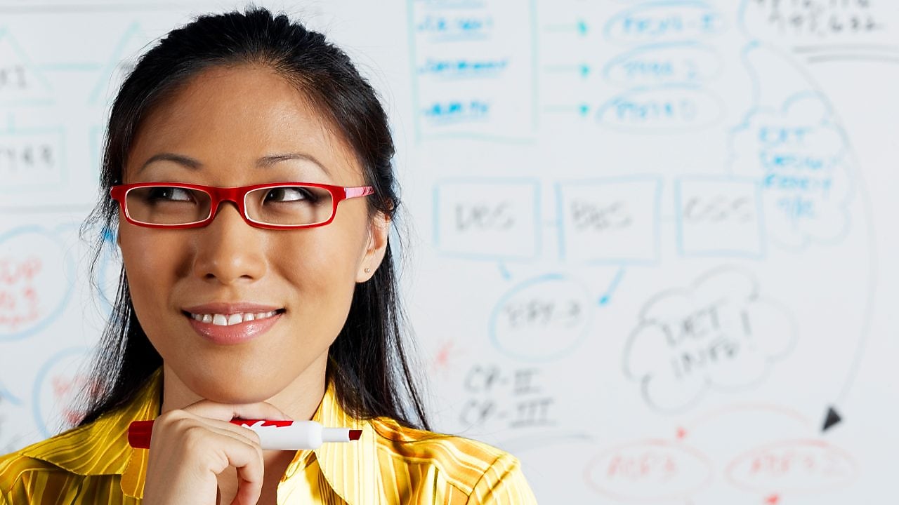 Close up of Asian businesswoman smiling in front of whiteboard