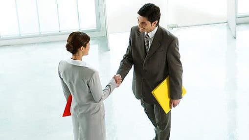 Businessman and businesswoman shaking hands in lobby