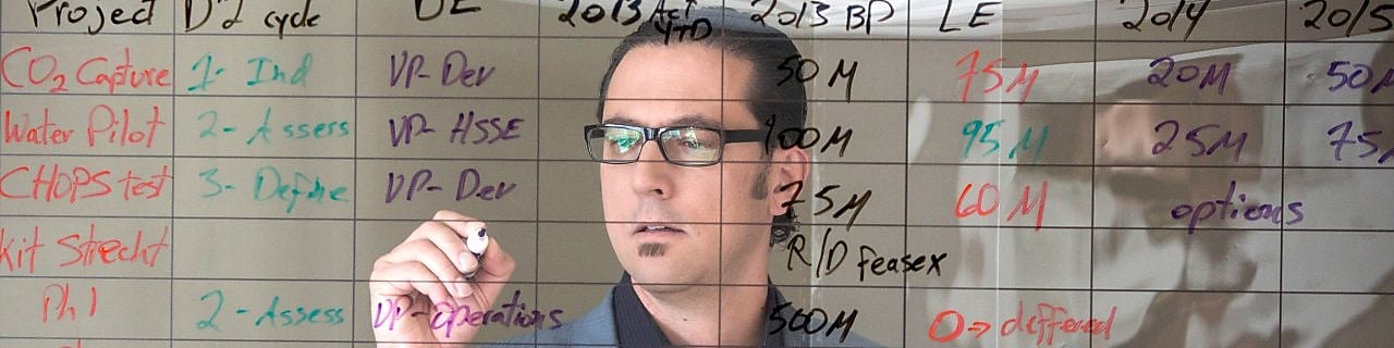 employee writing on transparent board.