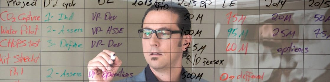 employee writing on transparent board.