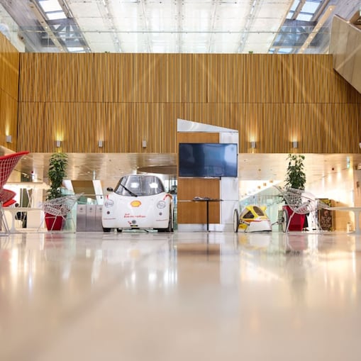 An internal image of the QSRTC lobby featuring experimental solar-powered vehicles, contemporary seating, and a large open atrium with wooden wall panels.