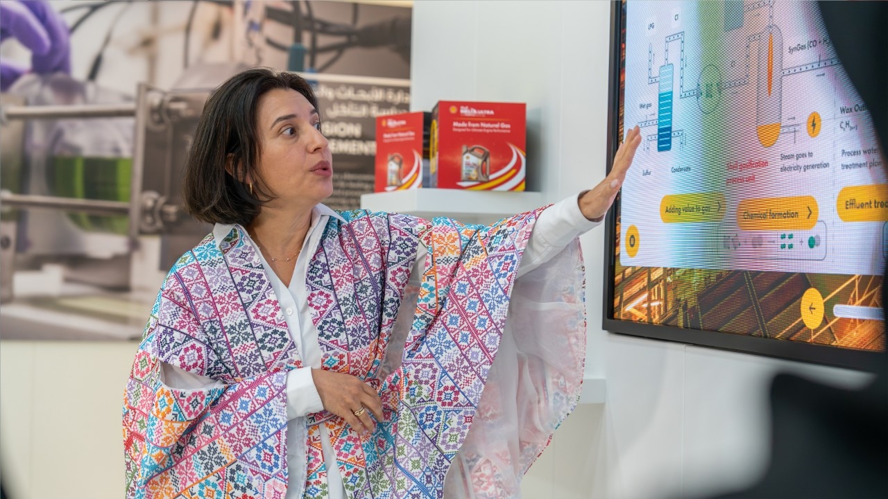 Close up image of a female is pointing at content on a large digital screen.