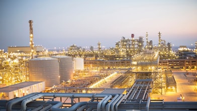 An external view of a gas-to-liquids production plant at night with lots of lit up areas.